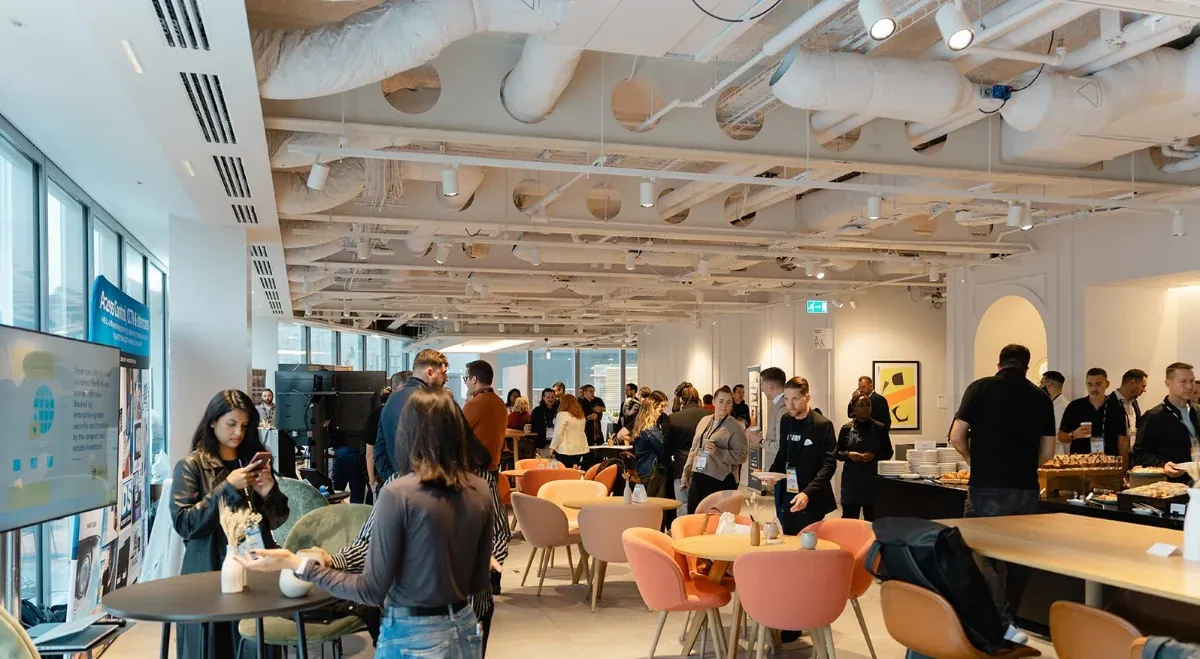 Attendees mingling in an open-plan event space with exposed ceiling services
